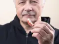 Starszy mężczyzna trzyma protezę. Dowiedz się, jak usunąć klej do protez z dziąseł, aby zapewnić komfort.