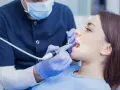 Dentysta wykonuje zabieg, a pacjentka zastanawia się, ile kosztuje znieczulenie u dentysty.