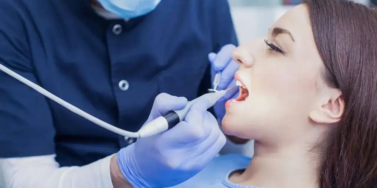 Dentysta wykonuje zabieg, a pacjentka zastanawia się, ile kosztuje znieczulenie u dentysty.